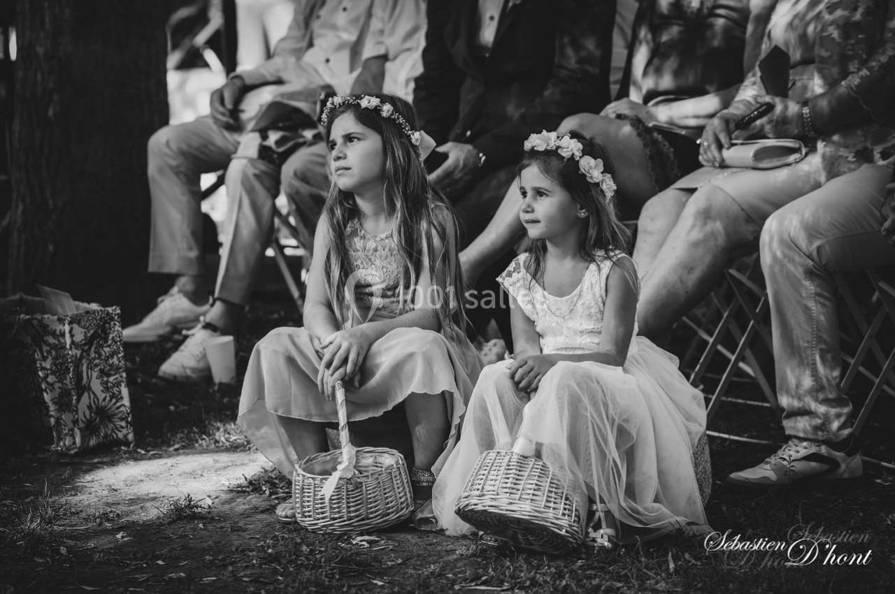 Deux jeunes filles assises sur l'herbe, portant des robes et des couronnes de fleurs, tenant des paniers en osier.
