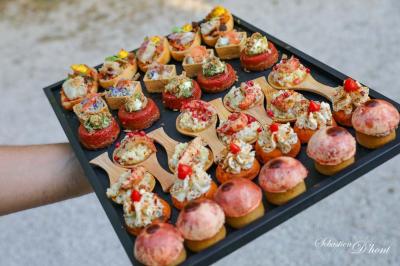 Salle de réception avec tables rondes dressées, nappes blanches, chaises en bois et décoration florale.
