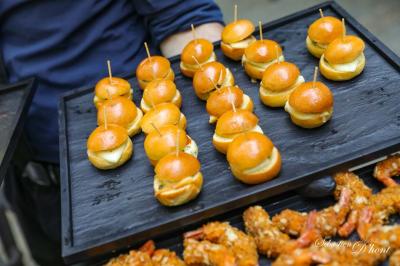 Salle de réception avec tables rondes dressées, nappes blanches, chaises en bois et décoration florale.
