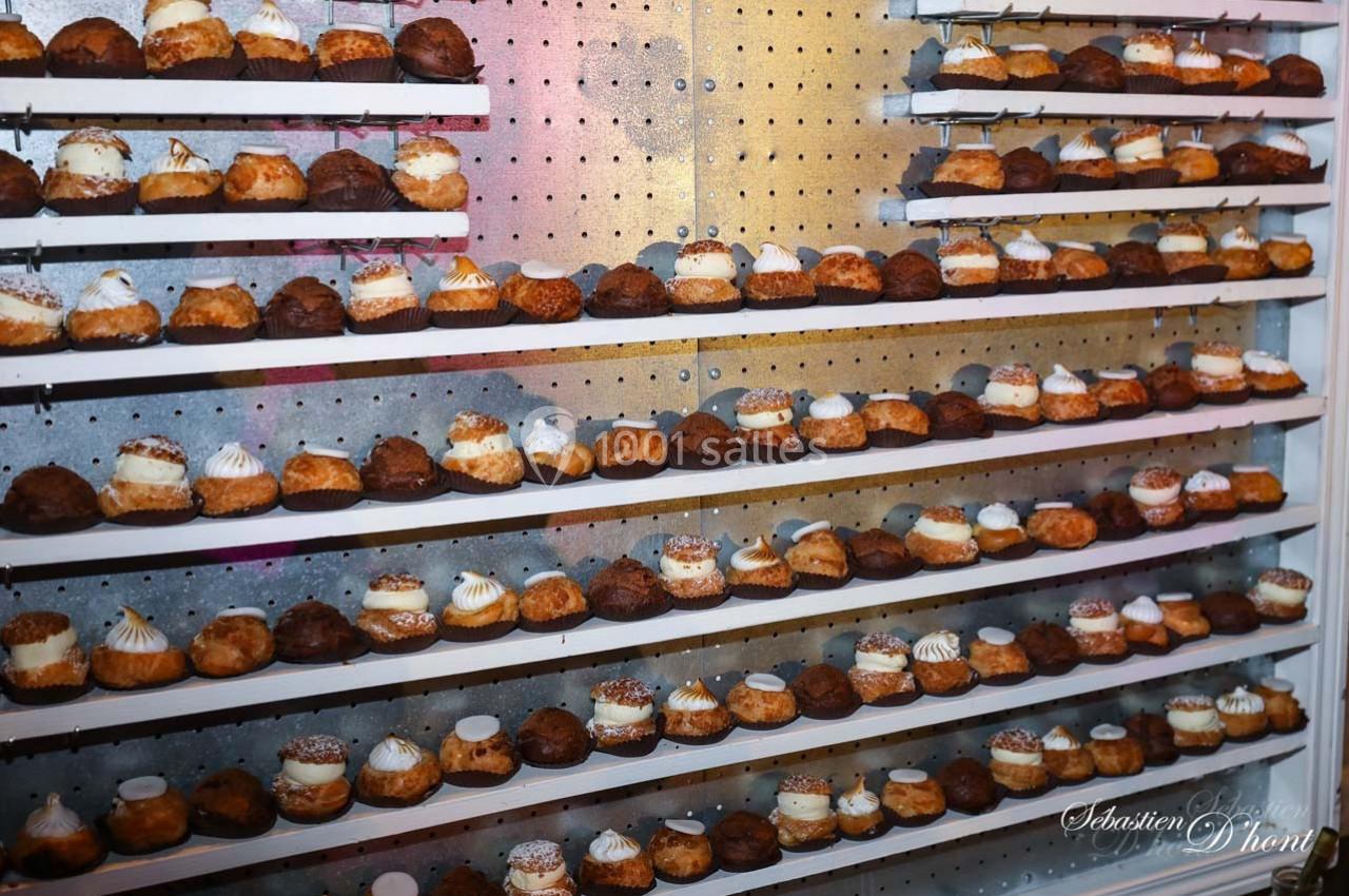 Étagères remplies de choux pâtissiers variés, alignés en rangées sur un fond perforé métallique.