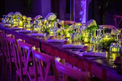 Salle de réception avec tables rondes dressées, nappes blanches, chaises en bois et décoration florale.