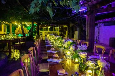 Salle de réception avec tables rondes dressées, nappes blanches, chaises en bois et décoration florale.