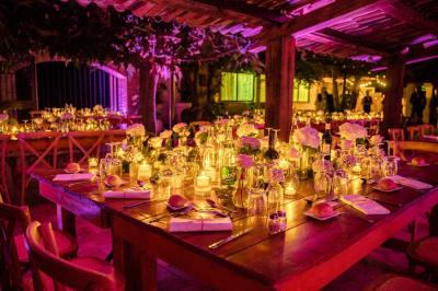 Salle de réception avec tables rondes dressées, nappes blanches, chaises en bois et décoration florale.