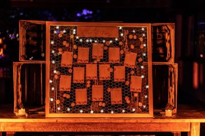 Salle de réception avec tables rondes dressées, nappes blanches, chaises en bois et décoration florale.