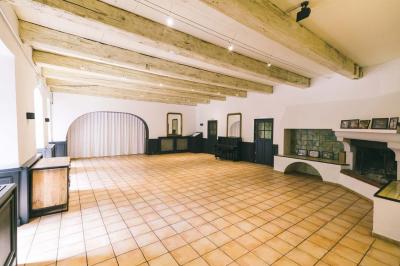 Salle de réception avec tables rondes dressées, nappes blanches, chaises en bois et décoration florale.