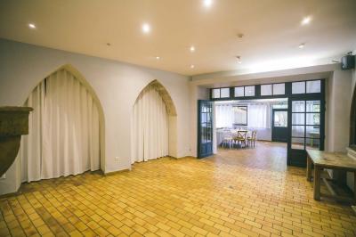 Salle de réception avec tables rondes dressées, nappes blanches, chaises en bois et décoration florale.