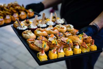 Salle de réception avec tables rondes dressées, nappes blanches, chaises en bois et décoration florale.