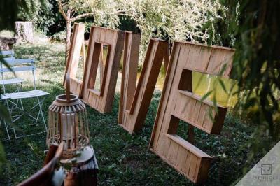 Salle de réception avec tables rondes dressées, nappes blanches, chaises en bois et décoration florale.