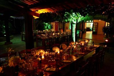 Salle de réception avec tables rondes dressées, nappes blanches, chaises en bois et décoration florale.