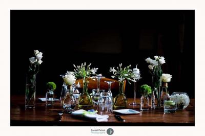 Salle de réception avec tables rondes dressées, nappes blanches, chaises en bois et décoration florale.