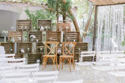 Salle de réception avec tables rondes dressées, nappes blanches, chaises en bois et décoration florale.