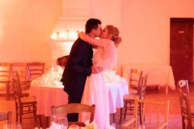 Salle de réception avec tables rondes dressées, nappes blanches, chaises en bois et décoration florale.