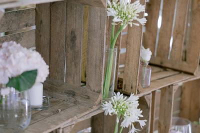 Salle de réception avec tables rondes dressées, nappes blanches, chaises en bois et décoration florale.