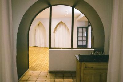 Salle de réception avec tables rondes dressées, nappes blanches, chaises en bois et décoration florale.