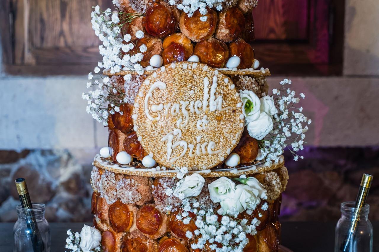 Pièce montée en choux décorée de fleurs blanches, de gypsophile et d'une plaque portant des prénoms.