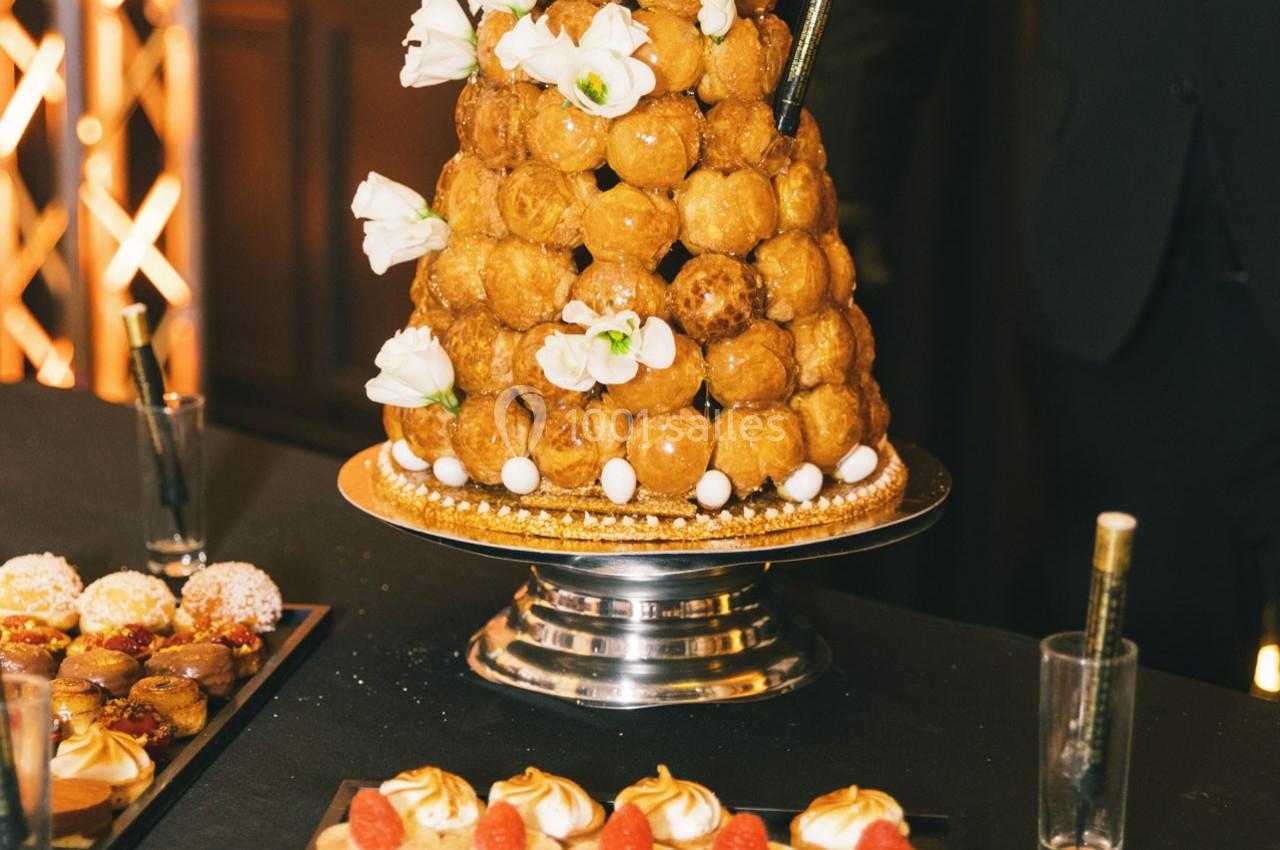 Pièce montée de choux décorée de fleurs blanches, présentée sur un plateau argenté lors d'un événement.