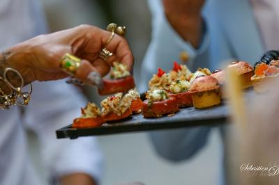 Salle de réception avec tables rondes dressées, nappes blanches, chaises en bois et décoration florale.