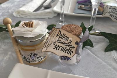 Un couple en tenue de mariage coupe une pièce montée décorée, devant un mur en pierre.