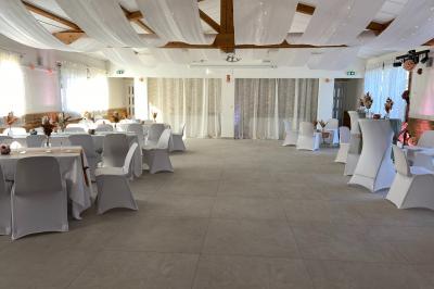 Un couple en tenue de mariage coupe une pièce montée décorée, devant un mur en pierre.