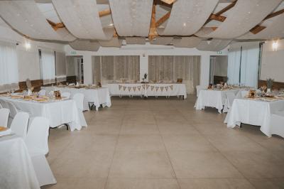 Un couple en tenue de mariage coupe une pièce montée décorée, devant un mur en pierre.