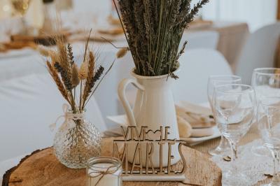 Un couple en tenue de mariage coupe une pièce montée décorée, devant un mur en pierre.