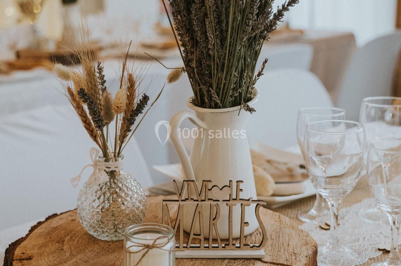 Centre de table rustique avec rondin de bois, bouquet de lavande, bougie et décoration ’Vive les mariés’.