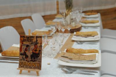 Un couple en tenue de mariage coupe une pièce montée décorée, devant un mur en pierre.