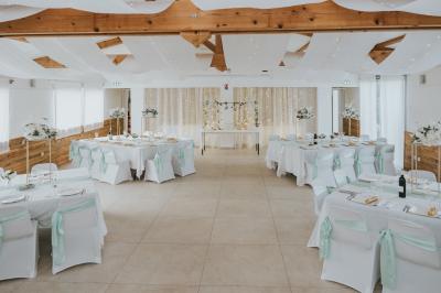 Un couple en tenue de mariage coupe une pièce montée décorée, devant un mur en pierre.