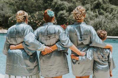 Un couple en tenue de mariage coupe une pièce montée décorée, devant un mur en pierre.