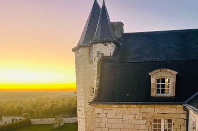 Miniature Location salle Marçay (Indre-et-Loire) - Château de Marcay #25 Chambre avec poutres apparentes, lit double, canapé beige, table basse en verre et murs décorés de papier peint.
