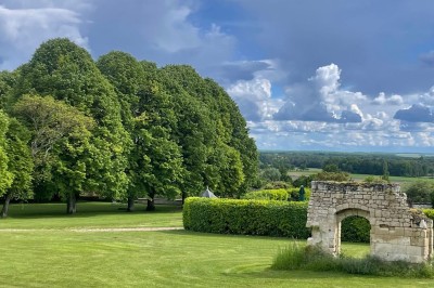 Miniature Location salle Marçay (Indre-et-Loire) - Château de Marcay #33 Chambre avec poutres apparentes, lit double, canapé beige, table basse en verre et murs décorés de papier peint.