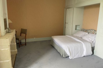 Miniature Location salle Marçay (Indre-et-Loire) - Château de Marcay #42 Chambre avec poutres apparentes, lit double, canapé beige, table basse en verre et murs décorés de papier peint.