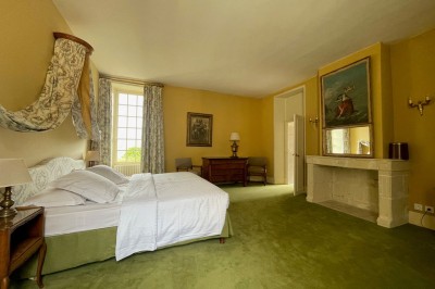 Miniature Location salle Marçay (Indre-et-Loire) - Château de Marcay #43 Chambre avec poutres apparentes, lit double, canapé beige, table basse en verre et murs décorés de papier peint.