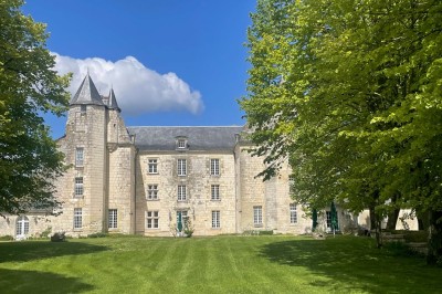 Miniature Location salle Marçay (Indre-et-Loire) - Château de Marcay #59 Chambre avec poutres apparentes, lit double, canapé beige, table basse en verre et murs décorés de papier peint.