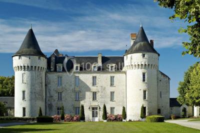 Miniature Location salle Marçay (Indre-et-Loire) - Château de Marcay #4 Chambre avec poutres apparentes, lit double, canapé beige, table basse en verre et murs décorés de papier peint.