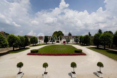 Miniature Location salle Marçay (Indre-et-Loire) - Château de Marcay #9 Chambre avec poutres apparentes, lit double, canapé beige, table basse en verre et murs décorés de papier peint.