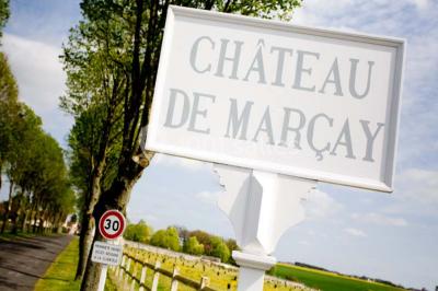 Miniature Location salle Marçay (Indre-et-Loire) - Château de Marcay #10 Chambre avec poutres apparentes, lit double, canapé beige, table basse en verre et murs décorés de papier peint.
