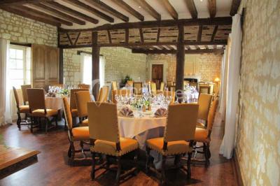 Miniature Location salle Marçay (Indre-et-Loire) - Château de Marcay #15 Chambre avec poutres apparentes, lit double, canapé beige, table basse en verre et murs décorés de papier peint.