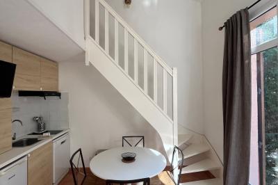 Table dressée avec assiettes en céramique, serviettes vertes pliées, couverts dorés, verres et décoration florale blanche.