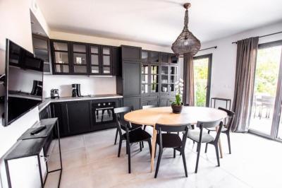 Table dressée avec assiettes en céramique, serviettes vertes pliées, couverts dorés, verres et décoration florale blanche.