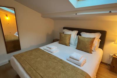 Table dressée avec assiettes en céramique, serviettes vertes pliées, couverts dorés, verres et décoration florale blanche.