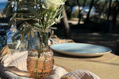 Table dressée avec assiettes en céramique, serviettes vertes pliées, couverts dorés, verres et décoration florale blanche.