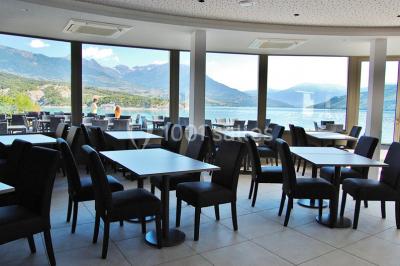Intérieur d'un mobil-home lumineux avec cuisine équipée, vue sur une terrasse et paysage montagneux à l'extérieur.