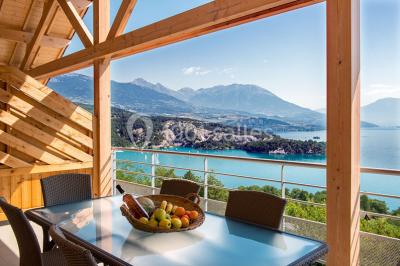 Intérieur d'un mobil-home lumineux avec cuisine équipée, vue sur une terrasse et paysage montagneux à l'extérieur.