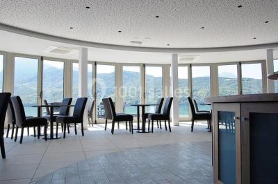 Intérieur d'un mobil-home lumineux avec cuisine équipée, vue sur une terrasse et paysage montagneux à l'extérieur.