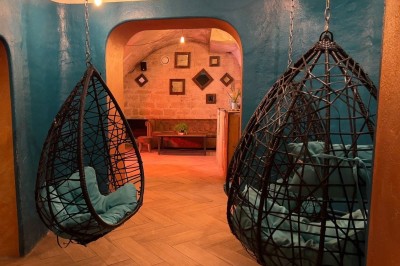 Fléchettes colorées dans une caisse en bois au premier plan, cible de jeu accrochée sur un mur en pierre en arrière-plan.