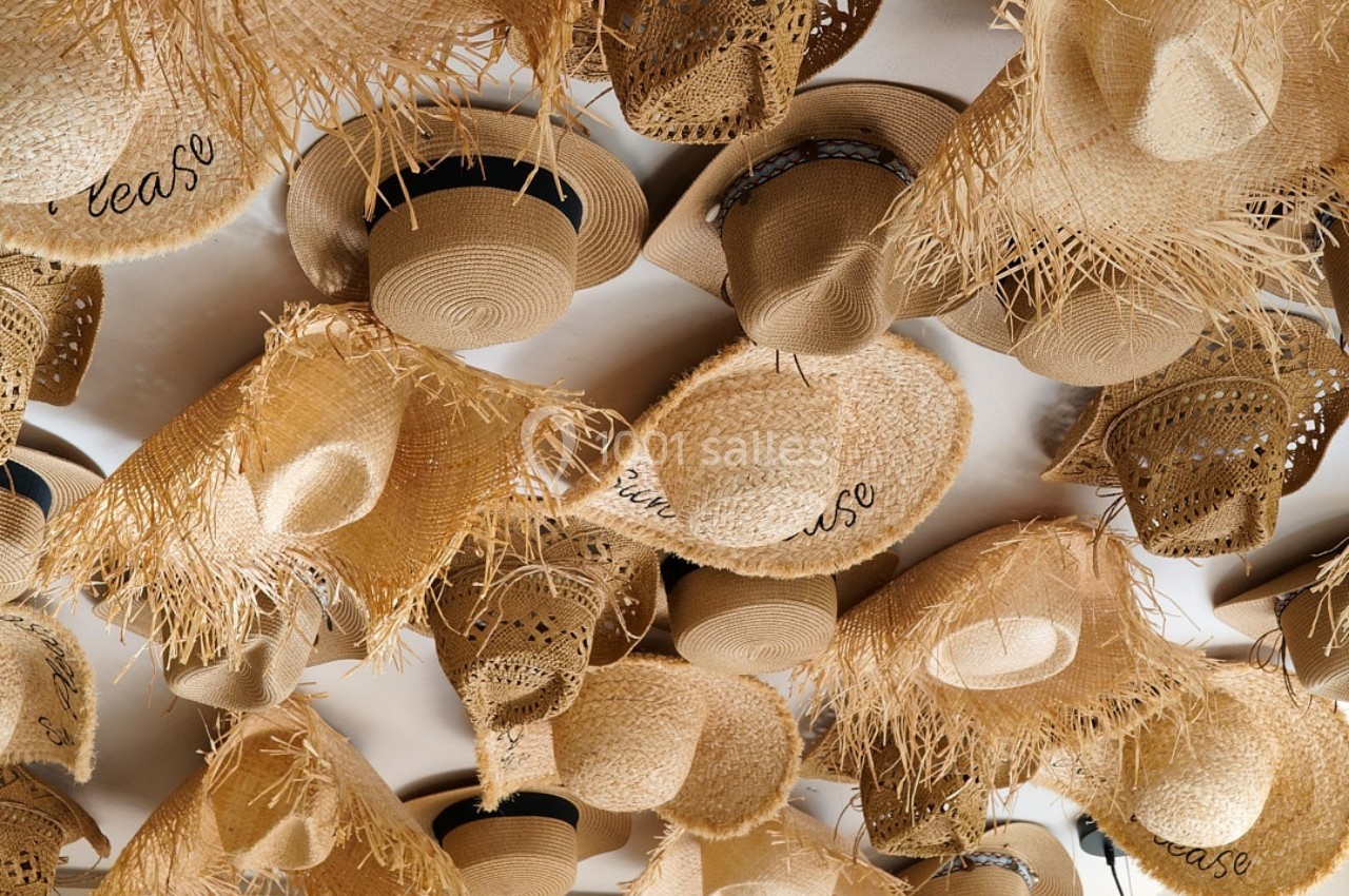 Chapeaux en paille suspendus au plafond, variés par leurs formes, motifs et ornements.