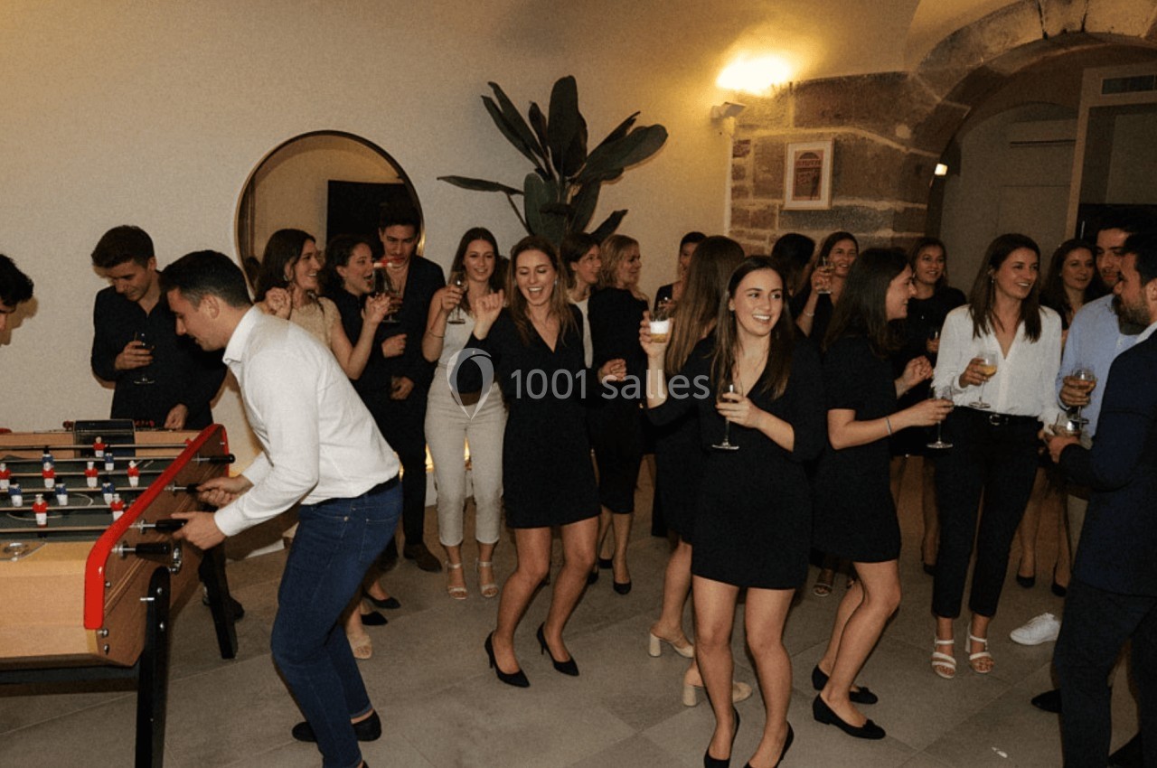 Des personnes dansent et discutent lors d'une soirée conviviale, avec un baby-foot au premier plan.