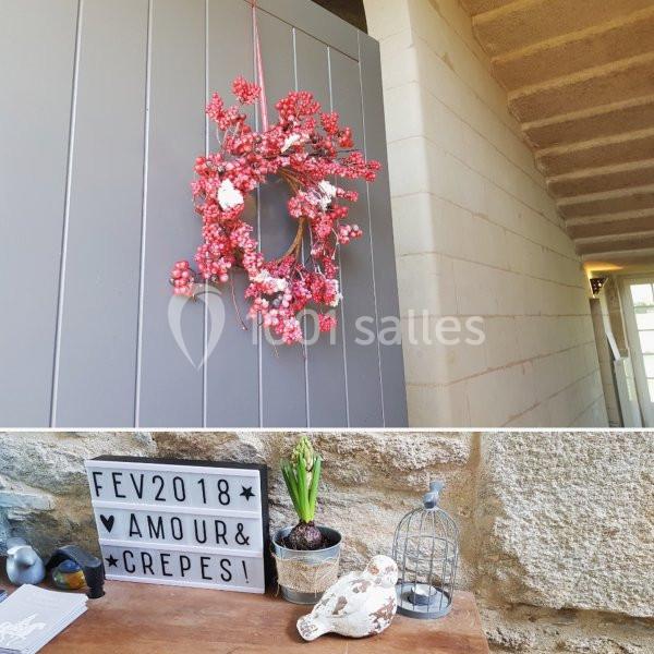 Couronne de baies rouges suspendue sur une porte grise et décor romantique avec objets et panneau ’Fév 2018 Amour & Crêpes’.