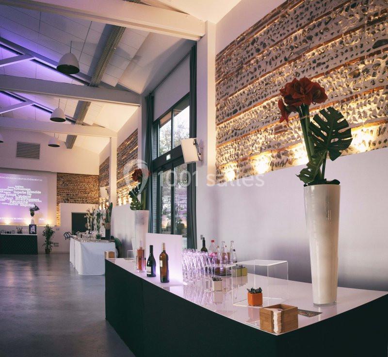 Salle de réception moderne avec tables dressées, décorations florales et éclairage tamisé.